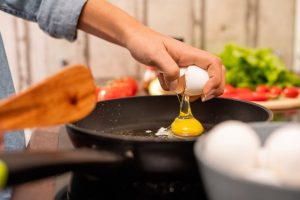 person making eggs in pan
